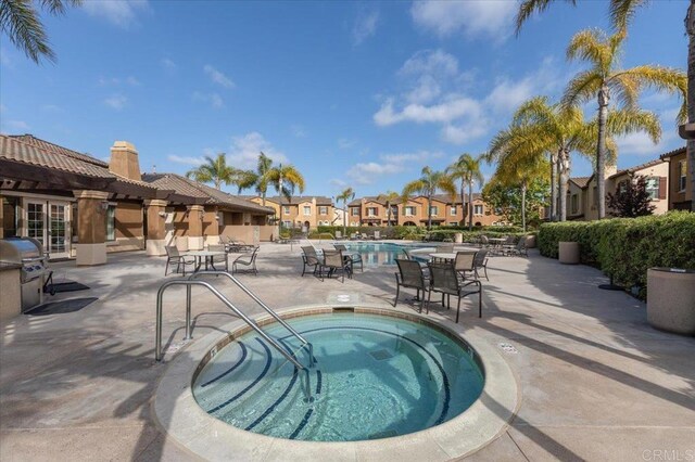 community pool with a residential view, a patio, a community hot tub, and a grill