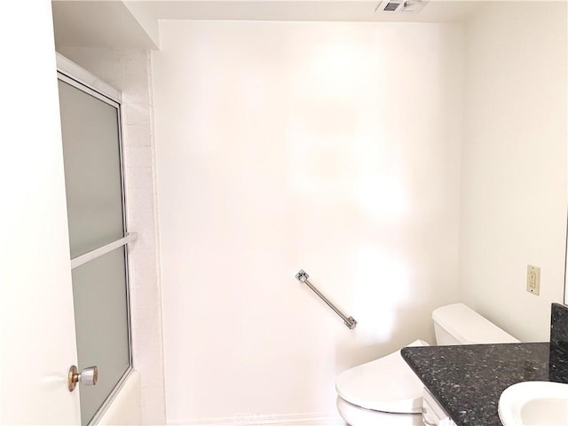 bathroom with vanity, toilet, shower / bath combination with glass door, and visible vents