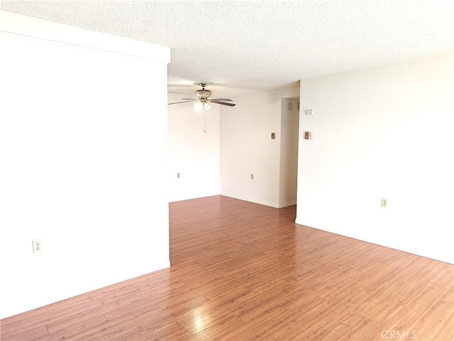 spare room featuring ceiling fan, light wood finished floors, and a textured ceiling