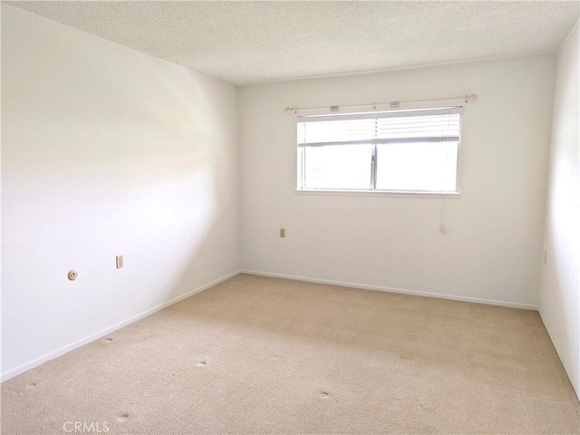 empty room with a textured ceiling, light carpet, and baseboards