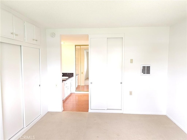 unfurnished bedroom featuring baseboards, visible vents, and light colored carpet