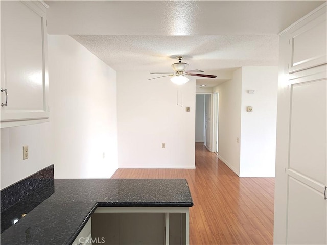 kitchen featuring a ceiling fan, a textured ceiling, light wood-type flooring, a peninsula, and white cabinetry