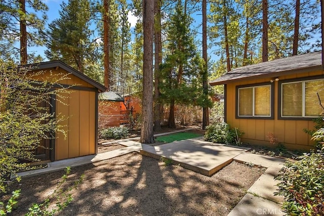 view of yard with an outdoor structure, a shed, and a patio area
