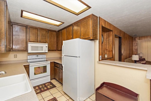 kitchen with light tile patterned floors, white appliances, light countertops, and a sink