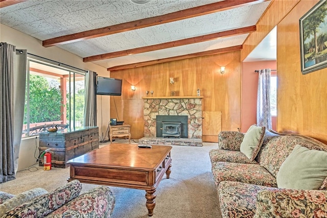 living area with beam ceiling, a wood stove, wooden walls, and carpet flooring