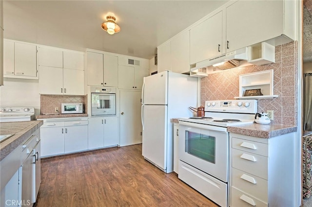 kitchen with tasteful backsplash, wood finished floors, white appliances, under cabinet range hood, and visible vents