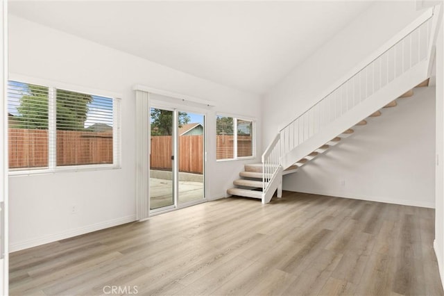 unfurnished living room featuring stairs, wood finished floors, and baseboards