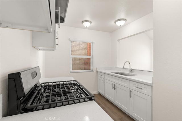 kitchen featuring white cabinets, a sink, light countertops, gas range, and wood finished floors