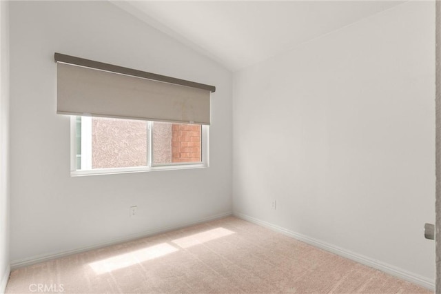 carpeted spare room featuring baseboards and vaulted ceiling
