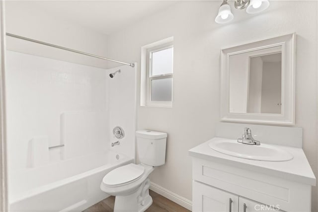 full bathroom with wood finished floors, toilet, vanity, baseboards, and tub / shower combination