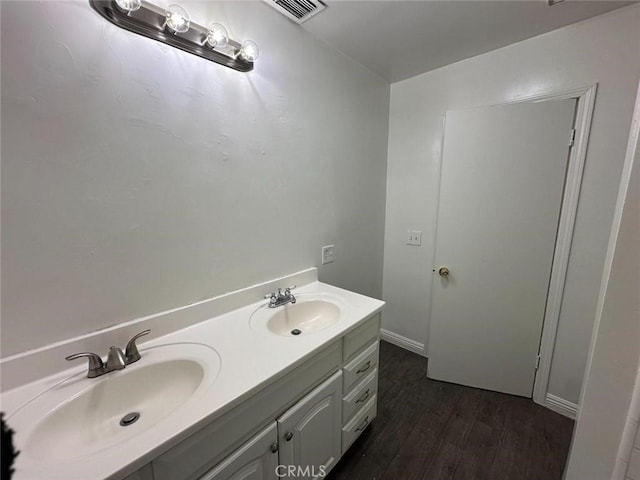 bathroom featuring double vanity, wood finished floors, visible vents, and a sink