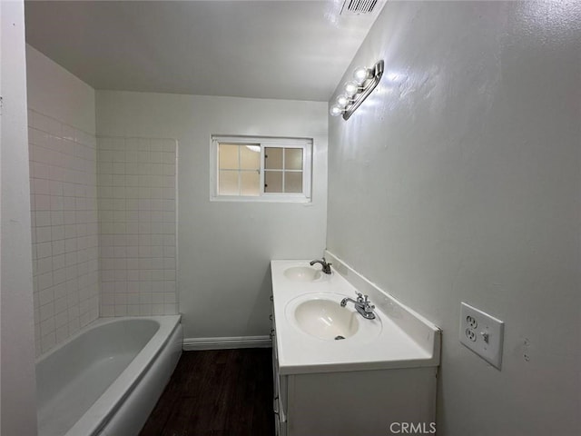 bathroom with wood finished floors, baseboards, visible vents, and a sink