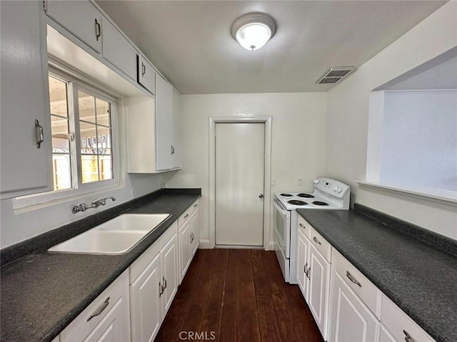 kitchen with white cabinets, dark countertops, a sink, visible vents, and white electric range oven