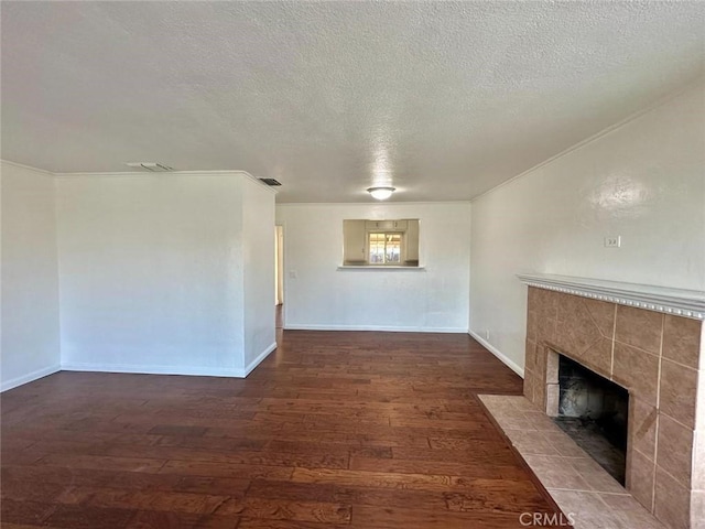 unfurnished living room featuring a tiled fireplace, crown molding, baseboards, a textured ceiling, and hardwood / wood-style floors