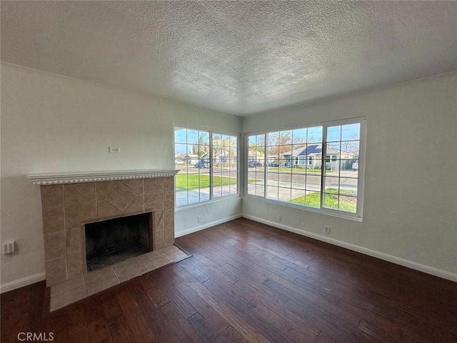 unfurnished living room with a fireplace, a textured ceiling, baseboards, and wood-type flooring