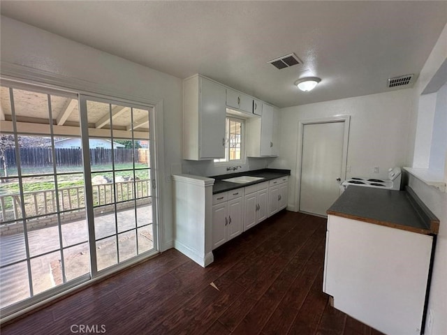 kitchen with dark countertops, a sink, dark wood-style flooring, and white electric stove