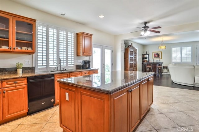kitchen with dark stone counters, dishwasher, a sink, a ceiling fan, and light tile patterned flooring