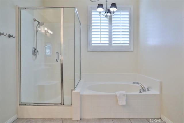 full bath featuring a garden tub, a shower stall, and a notable chandelier