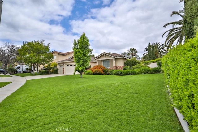 view of front of home featuring stucco siding, concrete driveway, a front yard, and a garage