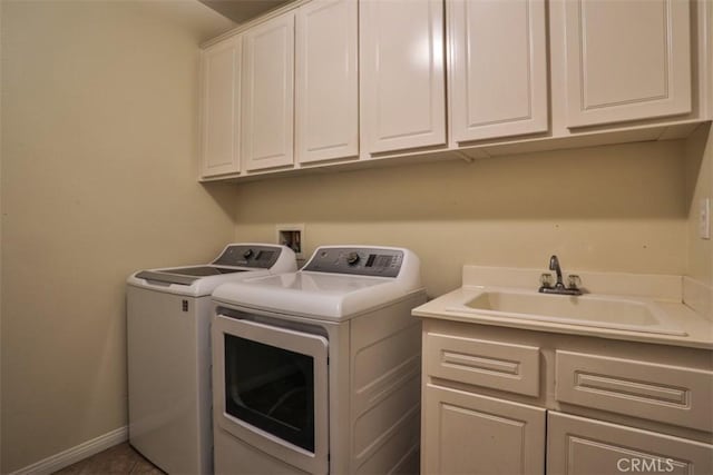 washroom with washing machine and clothes dryer, cabinet space, baseboards, and a sink