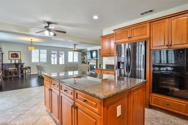 kitchen featuring visible vents, black appliances, ceiling fan, and brown cabinets