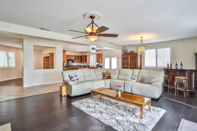 living area featuring visible vents, plenty of natural light, a ceiling fan, and baseboards