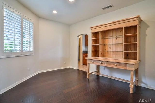interior space featuring arched walkways, visible vents, wood finished floors, and baseboards