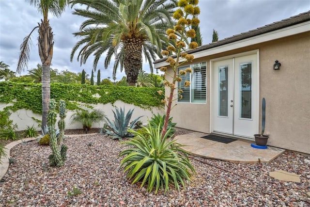 entrance to property with fence, french doors, and stucco siding