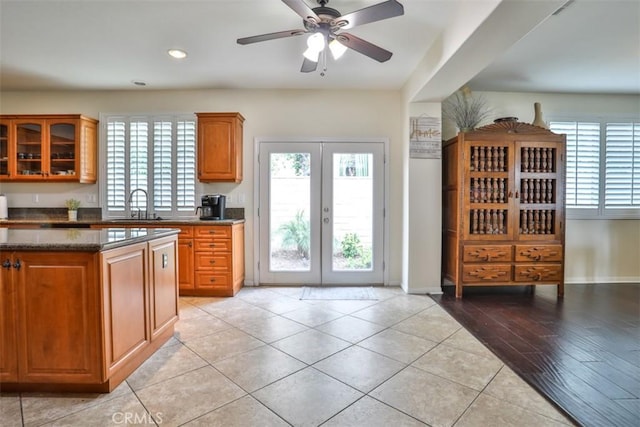 kitchen featuring brown cabinetry, glass insert cabinets, french doors, and a sink