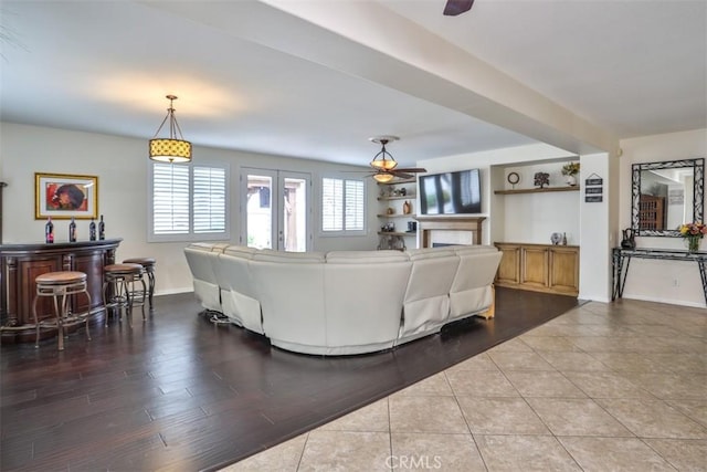 living area with ceiling fan, baseboards, wood finished floors, and a dry bar