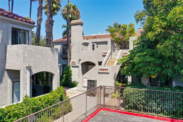 4752 Tiara Dr Unit 103, Huntington Beach, CA 92649 - view of front facade featuring stucco siding, a chimney, a tile roof, and a balcony