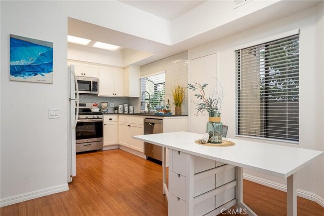 4752 Tiara Dr Unit 103, Huntington Beach, CA 92649 - kitchen with appliances with stainless steel finishes, light wood-style flooring, white cabinets, and baseboards