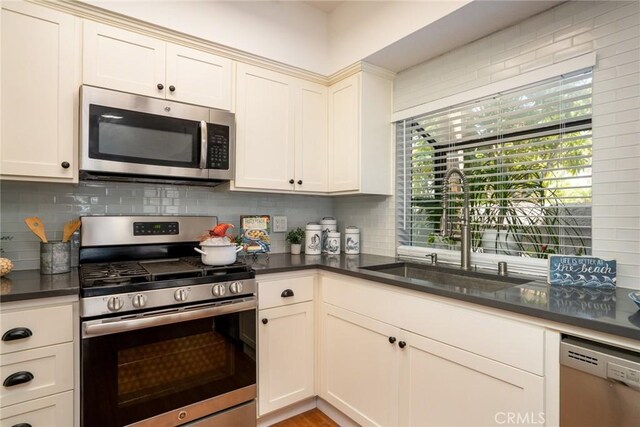 4752 Tiara Dr Unit 103, Huntington Beach, CA 92649 - kitchen featuring stainless steel appliances, a sink, dark countertops, and backsplash