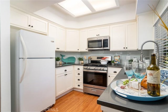 4752 Tiara Dr Unit 103, Huntington Beach, CA 92649 - kitchen with stainless steel appliances, dark countertops, light wood-style floors, and decorative backsplash