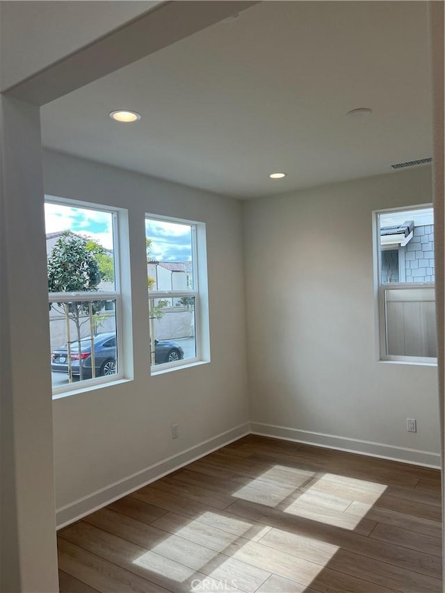 unfurnished room with recessed lighting, visible vents, wood finished floors, and baseboards