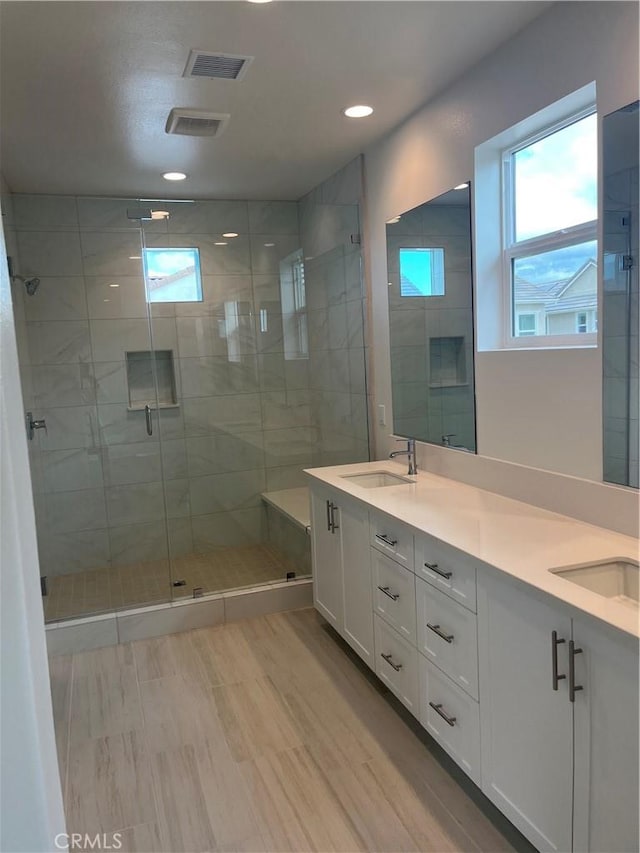 full bathroom featuring a stall shower, a sink, and a wealth of natural light