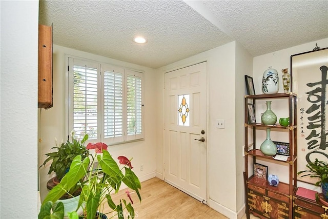 foyer with baseboards, a textured ceiling, and wood finished floors
