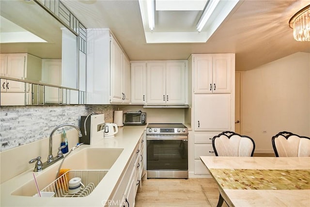 kitchen with a sink, light wood-style flooring, electric stove, white cabinetry, and backsplash