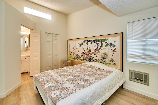 bedroom featuring light wood-style floors, a textured ceiling, baseboards, and a closet