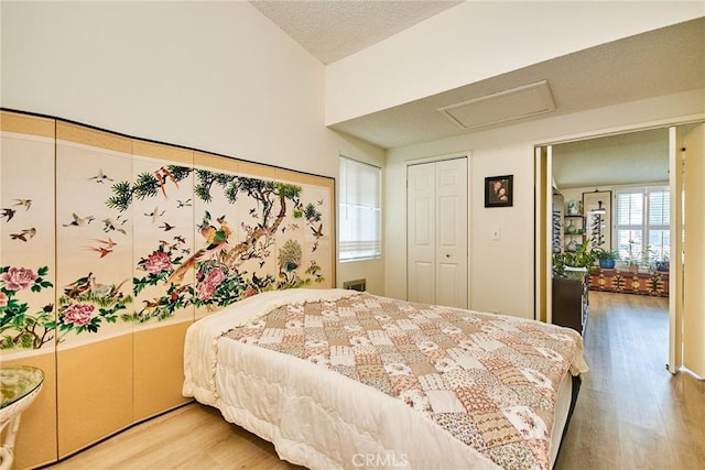 bedroom with a closet, attic access, and light wood finished floors