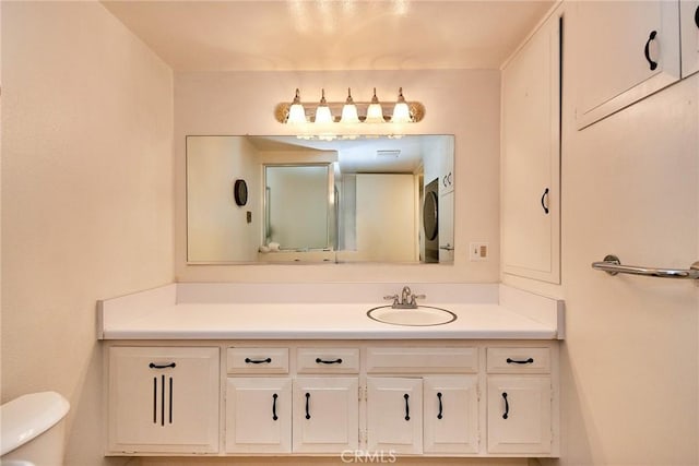 bathroom with vanity, stacked washer / dryer, and toilet
