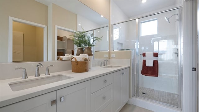 full bathroom with double vanity, a stall shower, and a sink