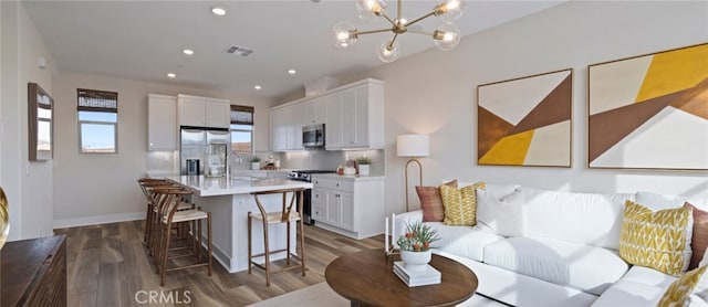 living area featuring visible vents, a chandelier, baseboards, recessed lighting, and wood finished floors