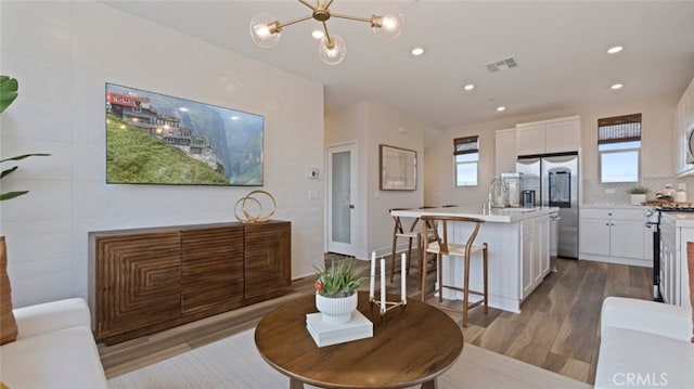 dining area with a chandelier, visible vents, wood finished floors, and recessed lighting