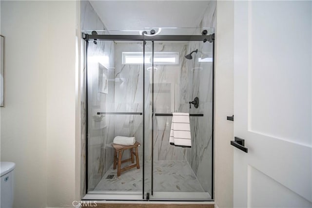 full bath with a marble finish shower and toilet