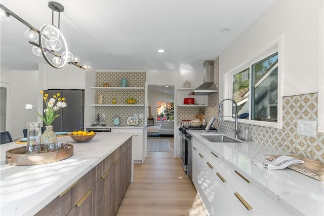 kitchen with open shelves, modern cabinets, wall chimney range hood, a sink, and appliances with stainless steel finishes