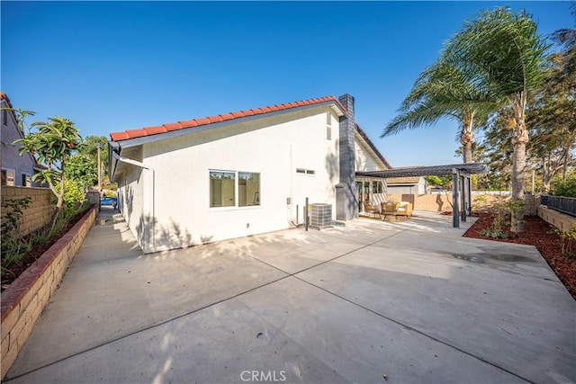 rear view of property with a chimney, a tile roof, a fenced backyard, a patio, and stucco siding