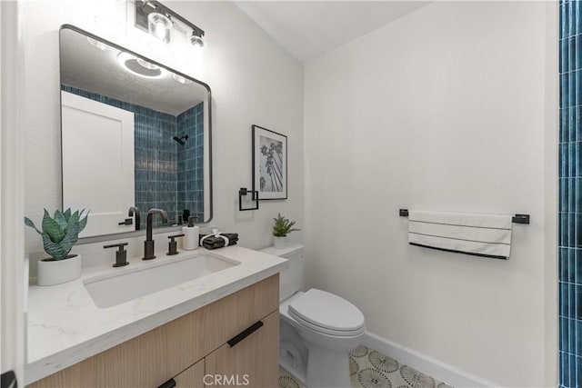 bathroom featuring toilet, a tile shower, tile patterned flooring, and vanity