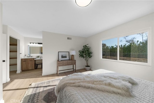 bedroom featuring light wood-type flooring, baseboards, ensuite bathroom, and visible vents