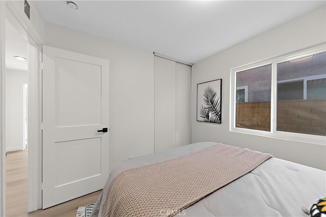 bedroom with a closet, light wood finished floors, and visible vents